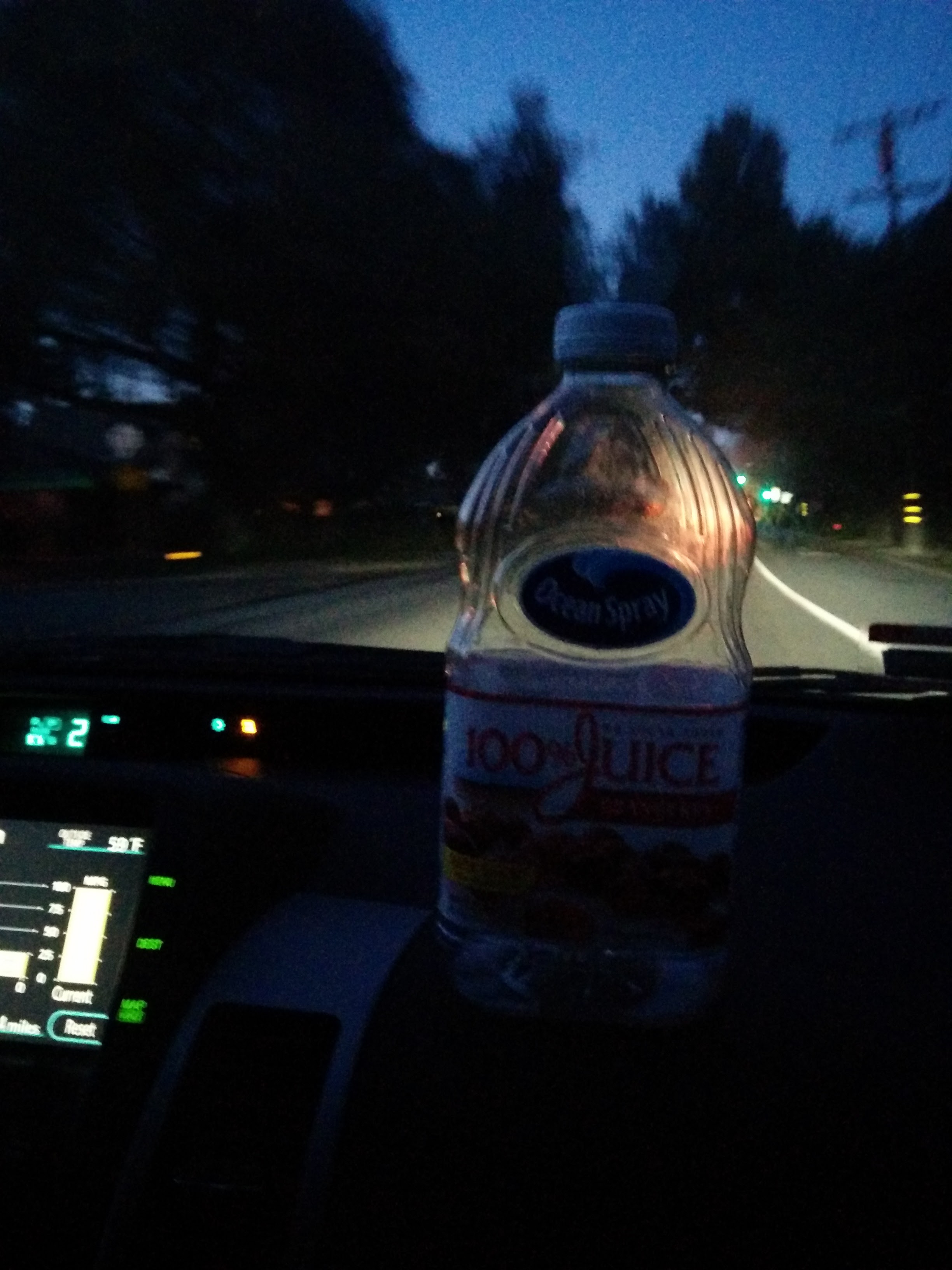 Inside of moving car with a large empty juice bottle sitting on the dashboard