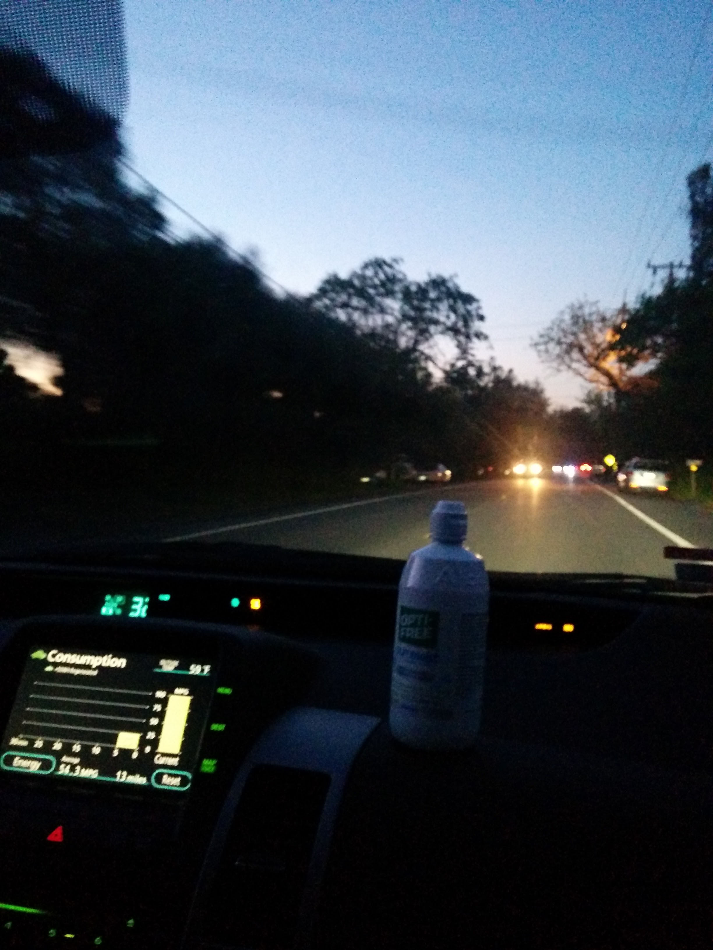 Inside of moving car with a large contact-lens solution bottle sitting on the dashboard