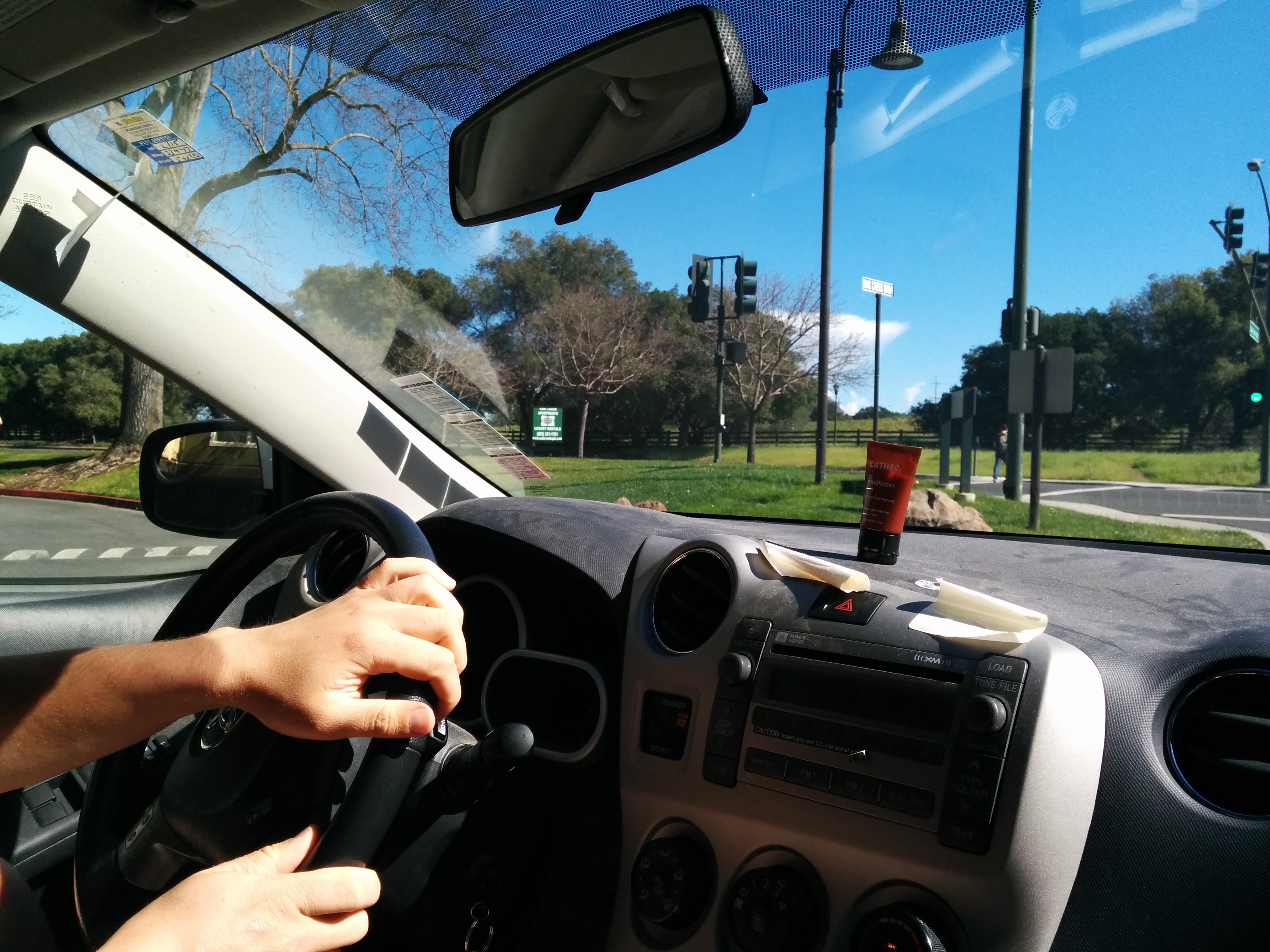 Inside of moving car with hotel-sized shampoo bottle sitting on the dashboard