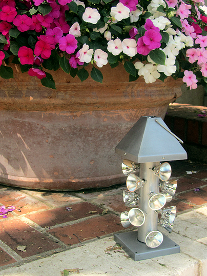 Lantern outside in the daytime, in front of a planter of flowers