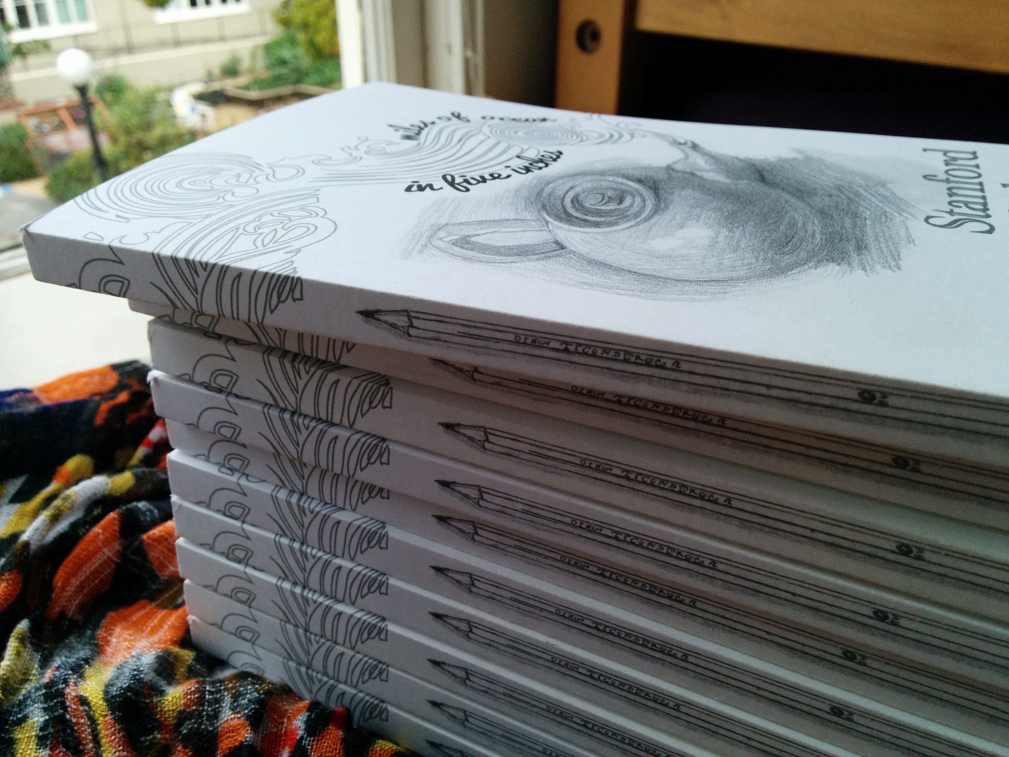 Stack of anthology copies with a drawing of a pencil on their spines